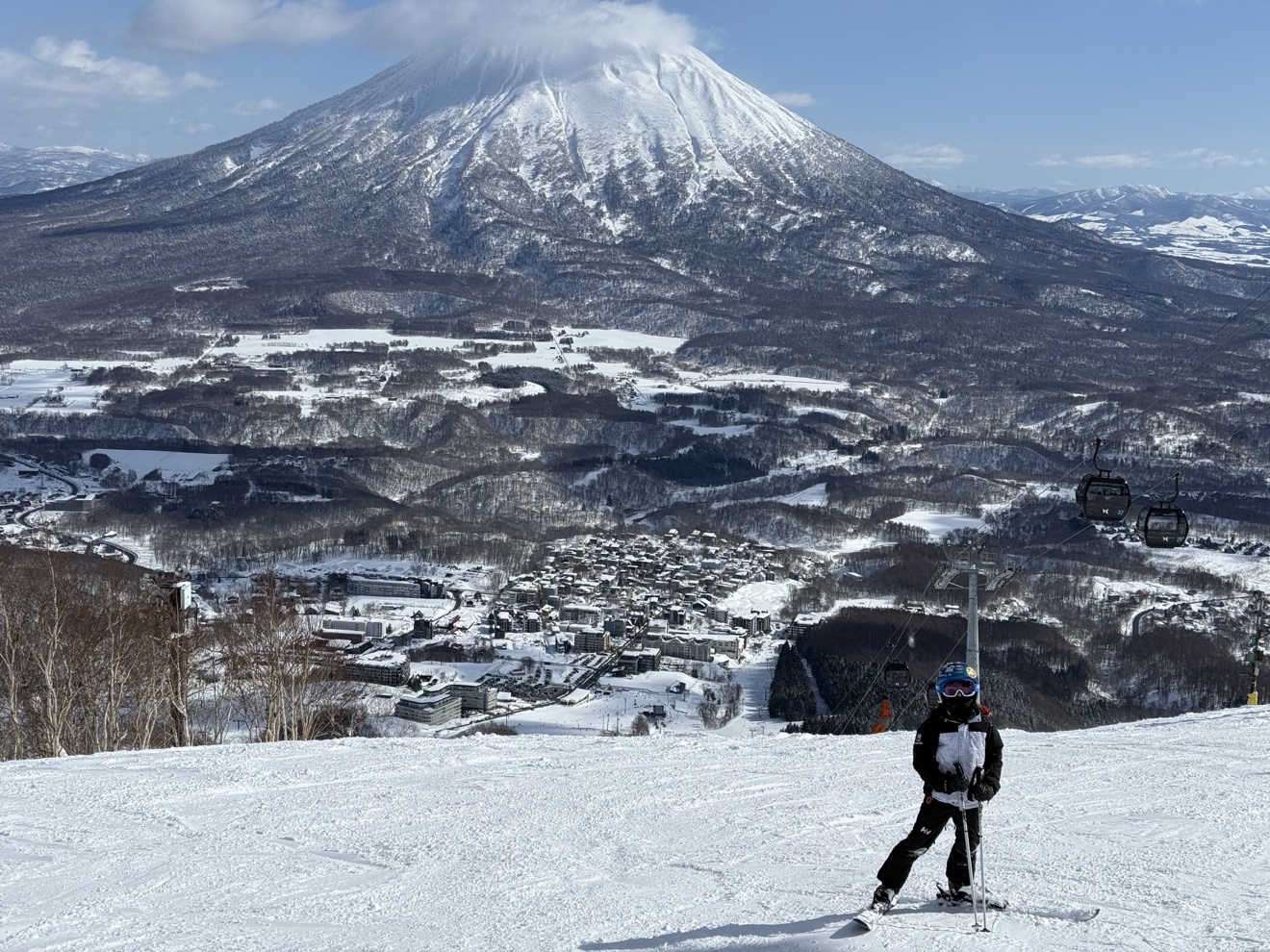 A skier above Niseko village with snow-covered Mount Yotei behind