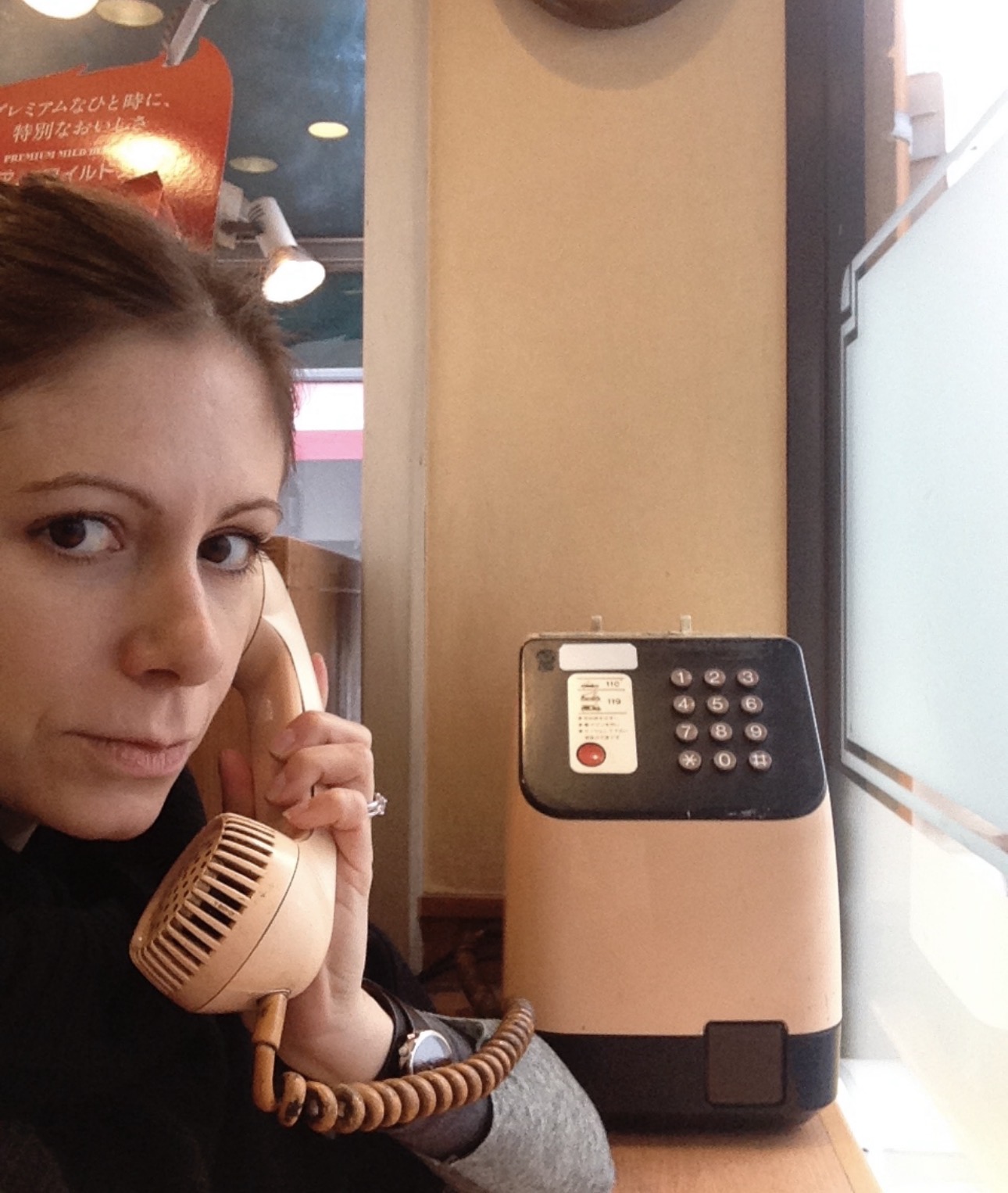 Tracey Delaney holding the handset of a vintage pink Japanese payphone to her ear